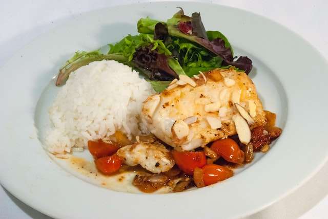 cod loin, almonds and tomato sauce, rice and side salad dish