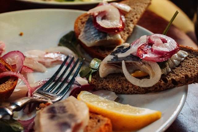 pickled herrings on rye bread, radish and red onion