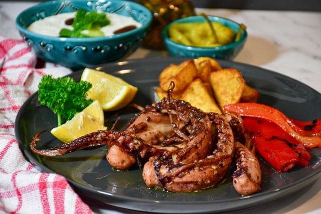 Octopus dish with potato wedges, roast peppers and garnish