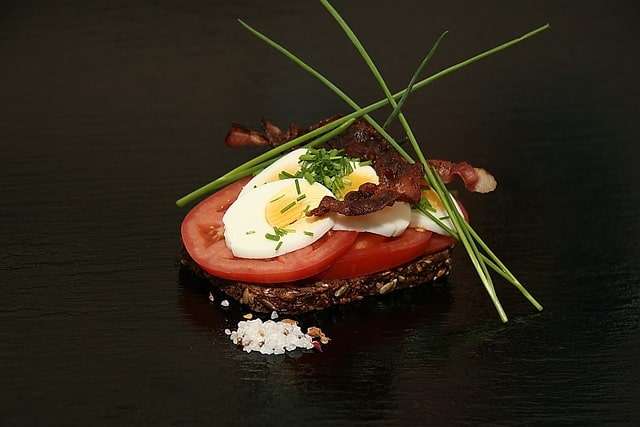 Rea bread open sandwiched with egg, tomato, bacon and herbs 