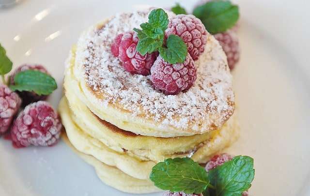 Pancakes top up with raspberry, mint leaves and icing sugar