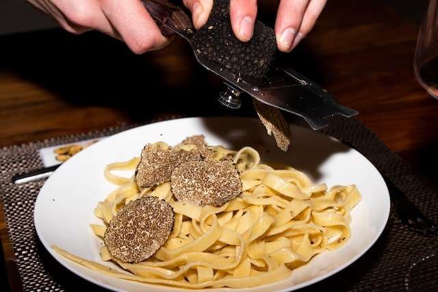 Shaving truffle on top of pasta dish